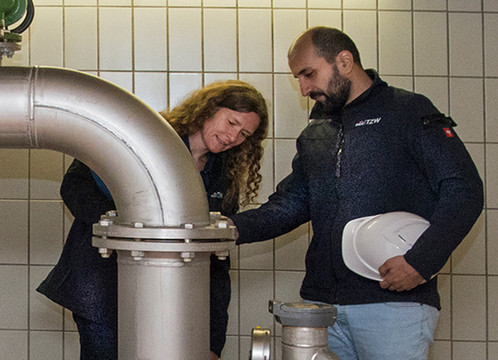 Zwei Mitarbeitende beraten sich an einer Wasserversorgungsanlage 